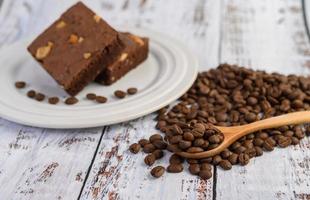 brownie al cioccolato su un piatto bianco e chicchi di caffè su un cucchiaio di legno foto