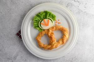 pretzel su un piatto bianco con lattuga e carote foto