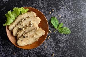 petto di pollo alla griglia cosparso di pepe e posto su un piatto di legno foto