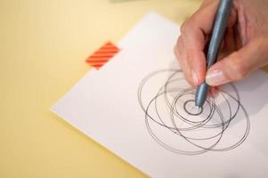 femmina mano utilizzando un' nero Magia penna preparazione per disegnare e schizzo il mandala concetto su il vuoto bianca carta. foto