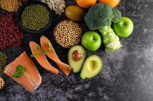 legumi, broccoli, frutta e salmone su uno sfondo di cemento nero foto