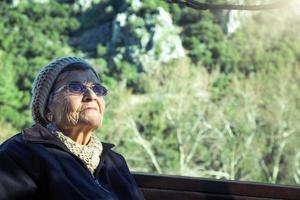 ritratto di un' anziano donna seduta su un' panchina nel il montagne foto