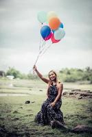 giovane donna che tiene palloncini colorati in natura foto