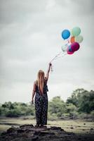 giovane donna che tiene palloncini colorati in natura