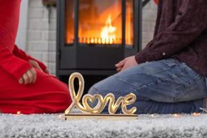 uomo e donna nel amore Data a casa siamo seduta vicino il camino stufa con un' ardente fuoco su un' accogliente tappeto. San Valentino giorno, contento coppia, amore storia, relazioni foto