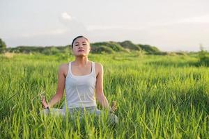 donna di yoga nella posizione del loto in un prato soleggiato foto