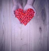 rosso cuore nel umano mano su giallo di legno sfondo foto