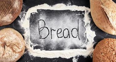 iscrizione pane su bianca Grano Farina sparpagliato, nel il angolo menzogna il giro al forno pagnotte di pane foto