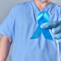 medico nel uniforme e latice guanti Tenere un' blu nastro nel il suo mano foto