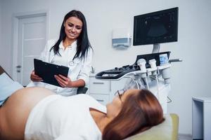 femmina medico parla di risultati di ultrasuono per un' incinta donna nel il ospedale foto