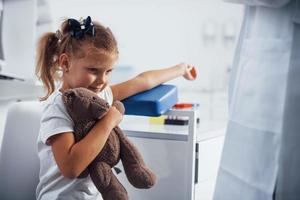 preparazione per sangue campionamento. poco ragazza con sua giocattolo nel mani è nel il clinica foto