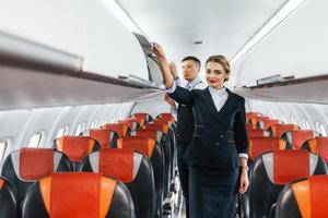 giovane hostess con steward su il opera nel il passanger aereo foto