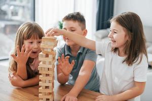 focalizzata su il confusione Torre gioco. bambini avendo divertimento nel il domestico camera a giorno insieme foto