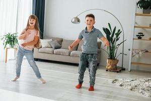 danza insieme. bambini avendo divertimento nel il domestico camera a giorno foto