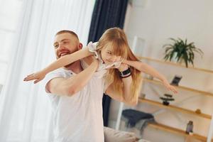 uomo Tenere ragazza nel mani. padre con il suo poco figlia è a casa insieme foto