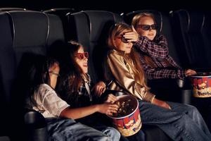 nel casuale Abiti. gruppo di bambini seduta nel cinema e Guardando film insieme foto