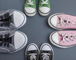 quattro coppie di vecchio tessile scarpe da ginnastica su un' nero sfondo foto