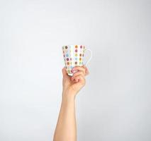 ceramica tazza con multicolore cerchi nel un' femmina mano su un' bianca sfondo foto