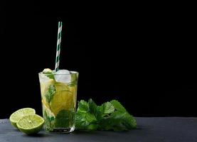 estate rinfrescante bevanda limonata con limoni, menta foglie, ghiaccio cubi e lime nel un' bicchiere foto