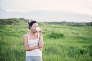 bella donna asiatica che beve caffè in un prato foto