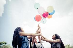 amiche del gruppo felice che tengono palloncini multicolori in un parco foto
