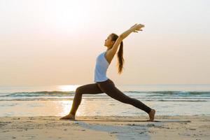 giovane asiatico donna fare yoga esercizio su il sabbia spiaggia nel il mattina a Alba. foto