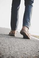 primo piano di giovane turista uomo che cammina su una strada di campagna foto