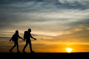sagome di due escursionisti con zaini che si godono il tramonto foto