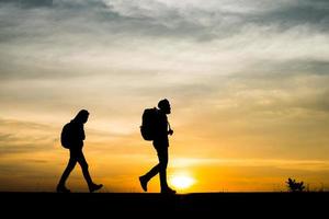 sagome di due escursionisti con zaini che si godono il tramonto
