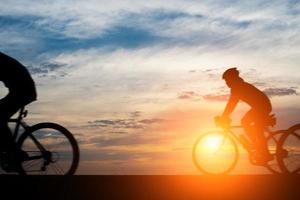 giovane cavalca una bicicletta su sfondo tramonto foto