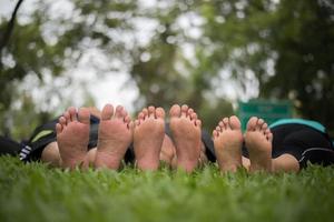 primo piano dei piedi della famiglia insieme su un campo verde foto