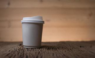 tazza di caffè di carta bianca sulla tavola di legno foto