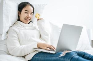 giovane donna shopping sul computer portatile e in possesso di una carta di credito foto