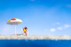persona in miniatura che prende il sole sulla spiaggia foto