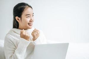 giovane donna che indossa una camicia bianca che gioca sul suo computer portatile foto