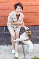 giovane donna giochi con sua cane su il erba su Giardino dietro la casa. il concetto di animali e amicizia o animale domestico proprietario e amore foto