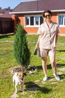 giovane donna indossare pigiama con sua cane su Giardino dietro la casa. concetto di animali e amicizia o animale domestico proprietario e amore foto