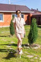 giovane donna indossare pigiama con sua cane su Giardino dietro la casa. il concetto di animali e amicizia o animale domestico proprietario e amore foto