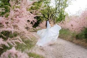 un' giovane ragazza sposa nel un' bianca vestito è Filatura su un' sentiero foto