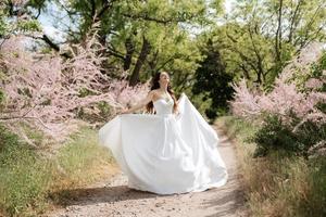 un' giovane ragazza sposa nel un' bianca vestito è Filatura su un' sentiero foto