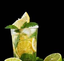 estate rinfrescante bevanda limonata con limoni, menta foglie, ghiaccio cubi e lime nel un' bicchiere foto