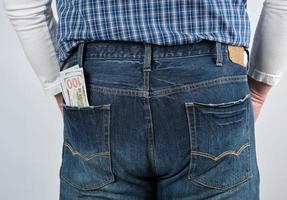 fascio di carta i soldi nel il indietro tasca di blu jeans foto