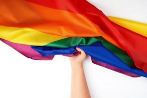 mano detiene tessile arcobaleno bandiera, simbolo di la libertà foto