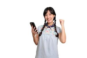 ritratto di contento bellissimo giovane asiatico donna nel denim vestito utilizzando un' smartphone su bianca sfondo. studio tiro foto