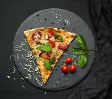 delizioso triangolare fetta di Pizza con affumicato salsicce, funghi, pomodori, formaggio e basilico le foglie foto