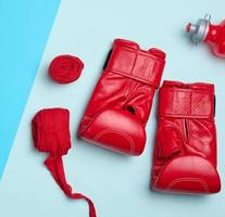 rosso pelle boxe guanti, tessile mano sostegno e acqua bottiglia. gli sport attrezzatura su un' blu sfondo foto