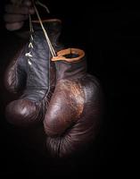 mano detiene un' paio di Marrone molto vecchio boxe guanti foto