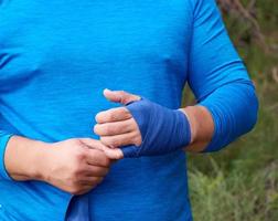 atleta In piedi e avvolgere il suo mani nel blu tessile elastico bendare foto