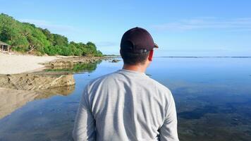 indietro di uomo indossare un' cappello chi è guardare a il blu spiagge, isole e bellissimo blu cielo foto