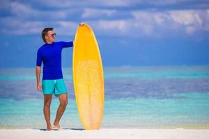 contento giovane Surf uomo a bianca spiaggia con giallo tavola da surf foto